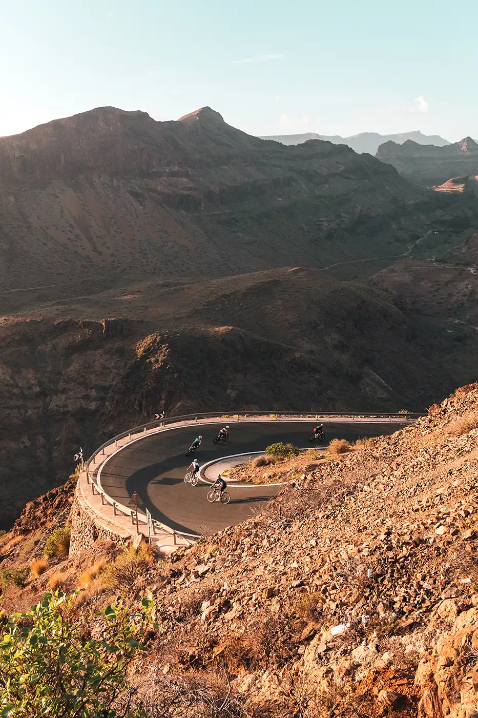 A cyclist on a hairpin bend carved into a red rock canyon in Gran Canaria